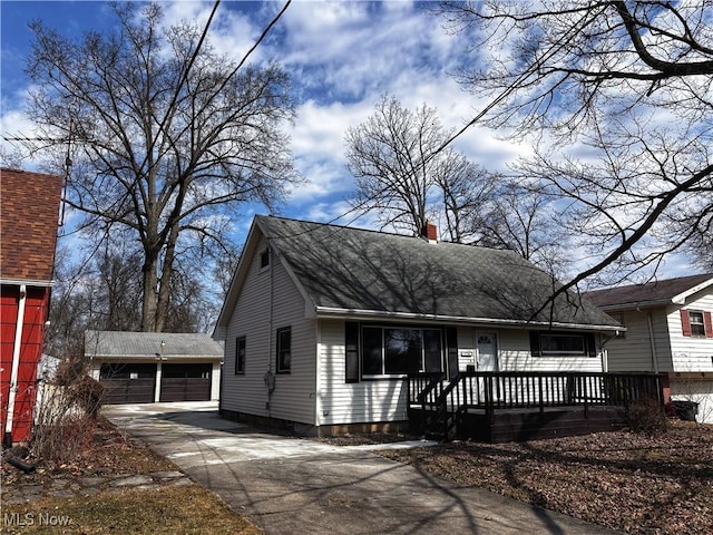 view of front of home featuring an outbuilding, a porch, a chimney, and a garage