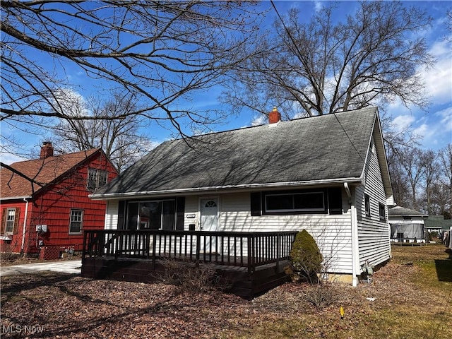 view of front facade featuring roof with shingles and a chimney