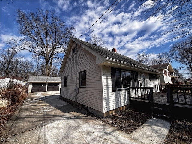 view of home's exterior with a detached garage, an outdoor structure, a chimney, and a deck