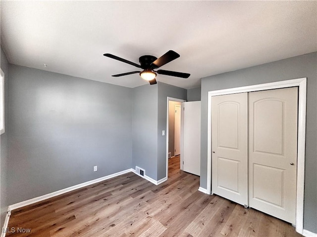 unfurnished bedroom featuring visible vents, ceiling fan, baseboards, wood finished floors, and a closet