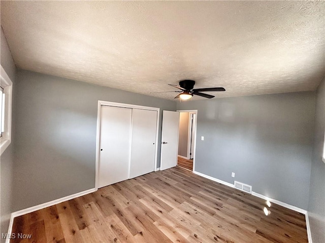 unfurnished bedroom with visible vents, baseboards, a closet, and wood finished floors