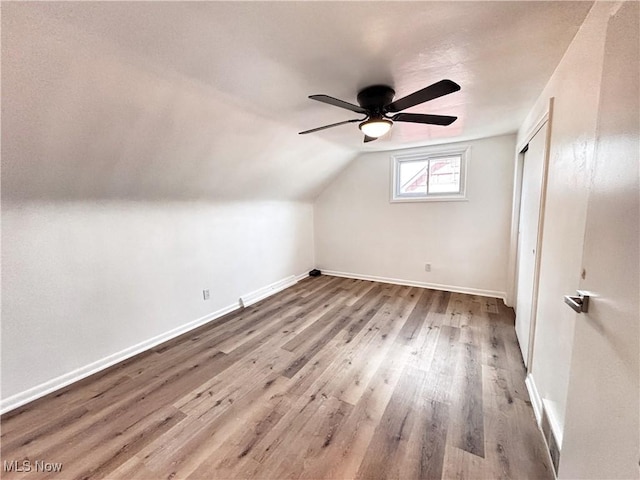 bonus room featuring baseboards, lofted ceiling, wood finished floors, and a ceiling fan