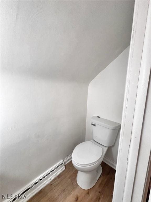 bathroom featuring toilet, lofted ceiling, wood finished floors, baseboards, and baseboard heating