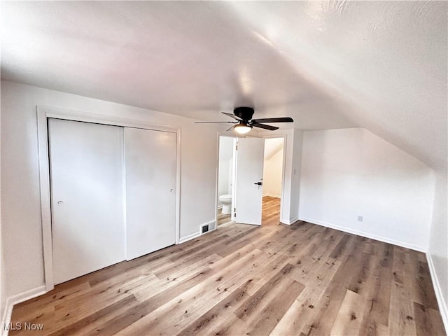 unfurnished bedroom with a closet, visible vents, lofted ceiling, and wood finished floors