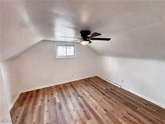 bonus room with baseboards, lofted ceiling, wood finished floors, a ceiling fan, and a baseboard radiator