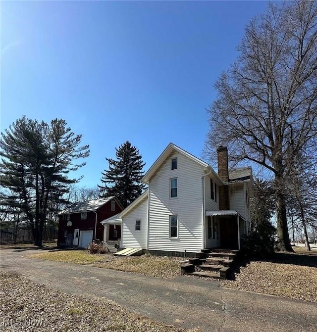 view of home's exterior with entry steps, a chimney, and a garage