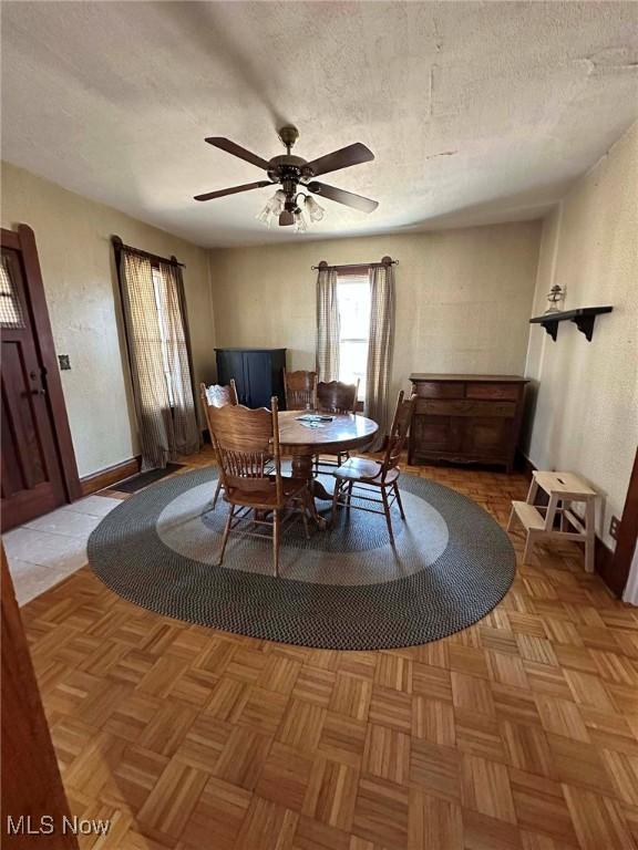 dining space featuring baseboards, a textured ceiling, and ceiling fan