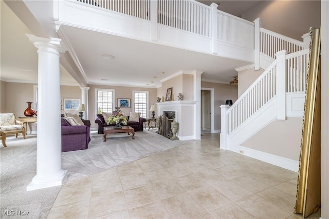 living area featuring carpet, stairs, ornamental molding, decorative columns, and a fireplace