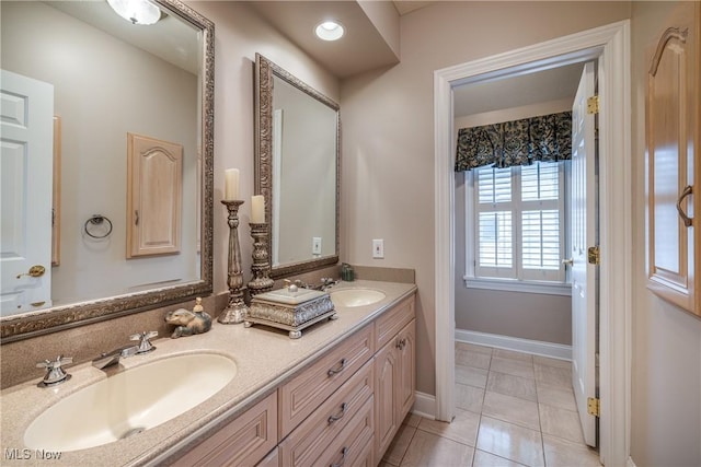 bathroom featuring a sink, baseboards, double vanity, and tile patterned floors