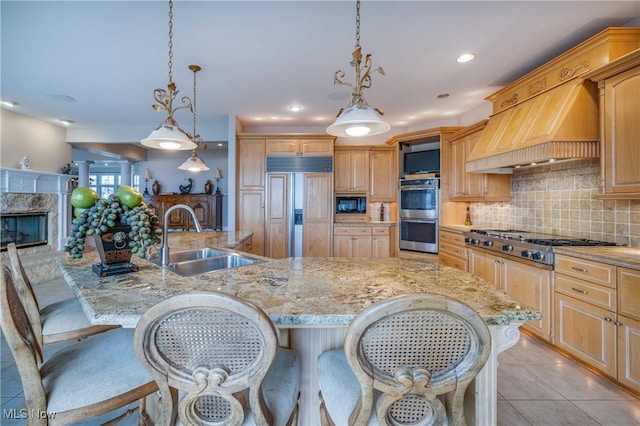 kitchen with a fireplace, a sink, custom range hood, built in appliances, and tasteful backsplash