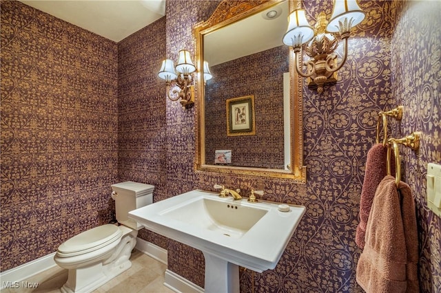 half bathroom with tile patterned flooring, wallpapered walls, toilet, and baseboards