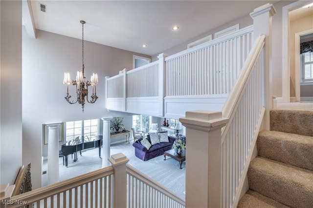 stairway with visible vents, carpet, a chandelier, recessed lighting, and a high ceiling