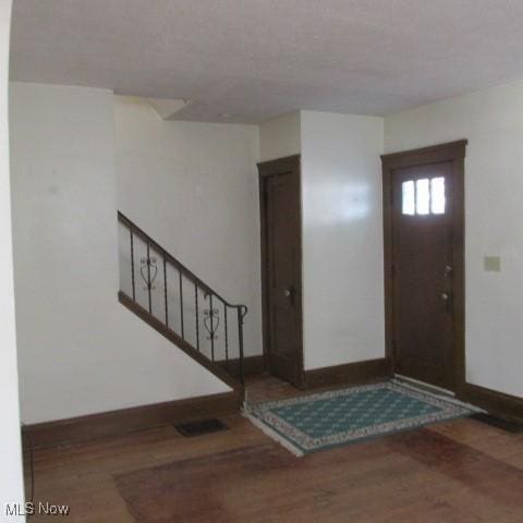 foyer entrance with stairs, baseboards, and wood finished floors