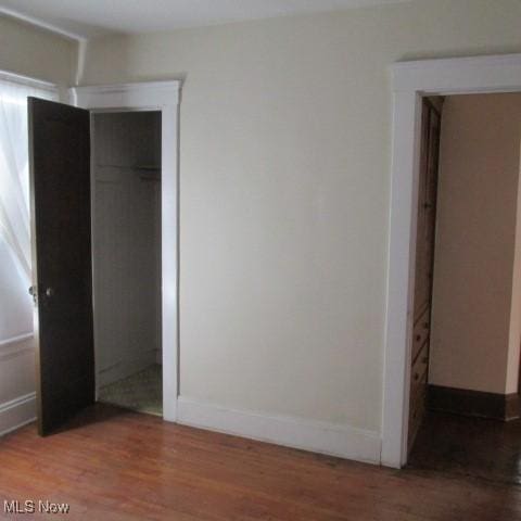 unfurnished bedroom with a closet, baseboards, and wood finished floors