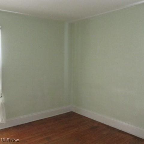 empty room featuring baseboards and dark wood-style flooring