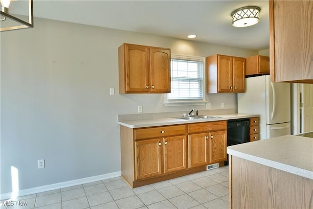 kitchen featuring visible vents, a sink, freestanding refrigerator, light countertops, and dishwasher