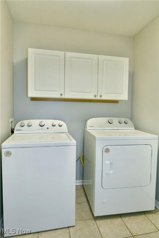 washroom featuring light tile patterned floors, cabinet space, and washer and clothes dryer