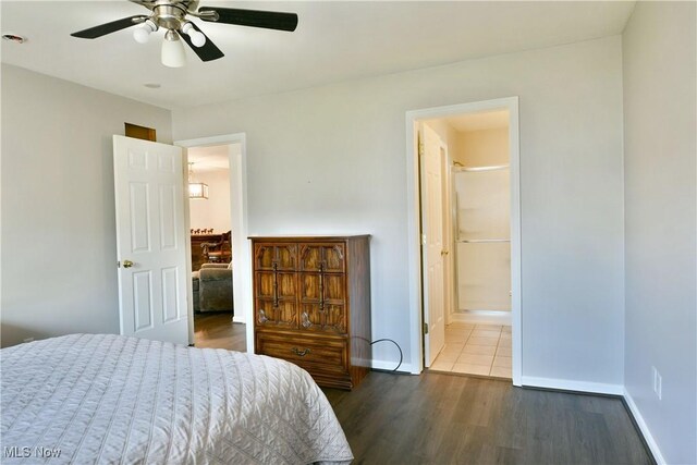 bedroom with ensuite bath, dark wood-type flooring, baseboards, and a ceiling fan