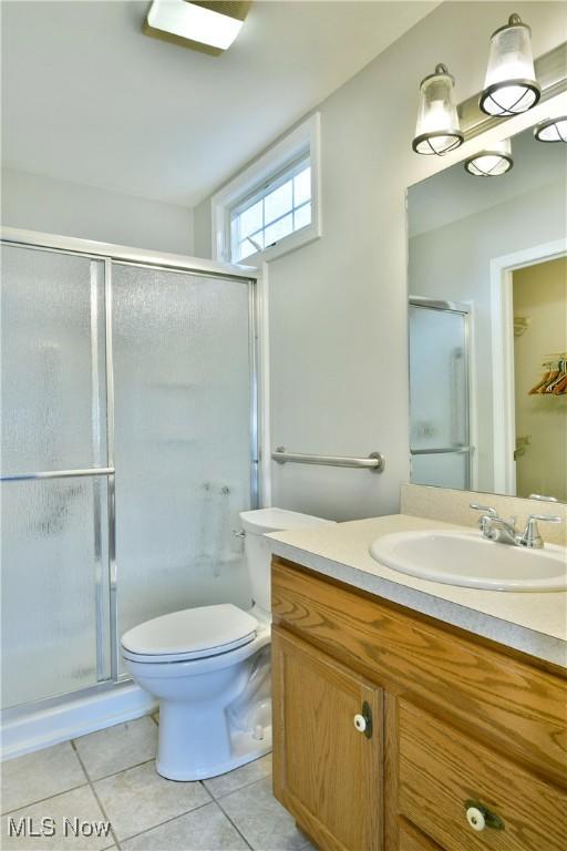 bathroom featuring toilet, a stall shower, vanity, and tile patterned flooring