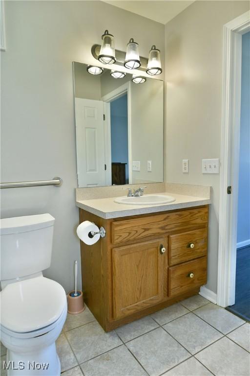 bathroom featuring baseboards, toilet, vanity, and tile patterned flooring