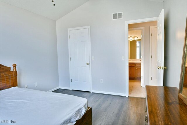 bedroom featuring visible vents, lofted ceiling, baseboards, and wood finished floors