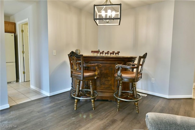 dining space with a dry bar, wood finished floors, baseboards, and a chandelier