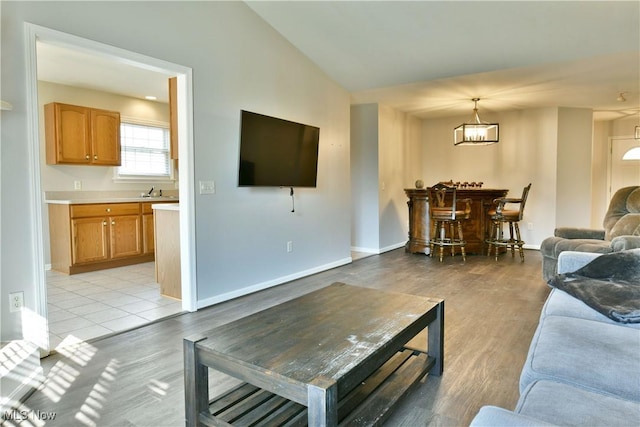 living room featuring baseboards, light wood-style floors, and vaulted ceiling