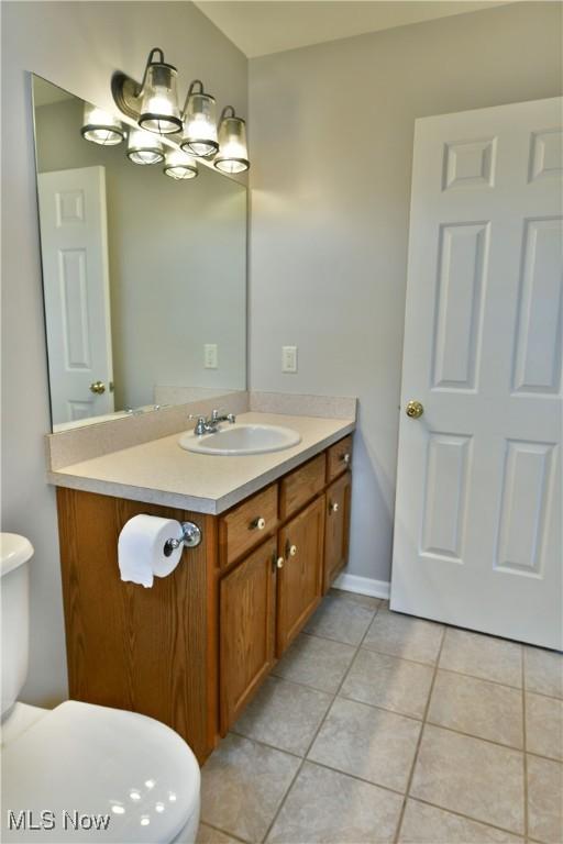 bathroom featuring tile patterned flooring, baseboards, toilet, an inviting chandelier, and vanity