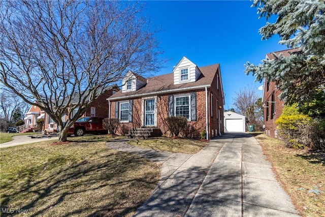 cape cod home with driveway, a front lawn, a detached garage, an outdoor structure, and brick siding