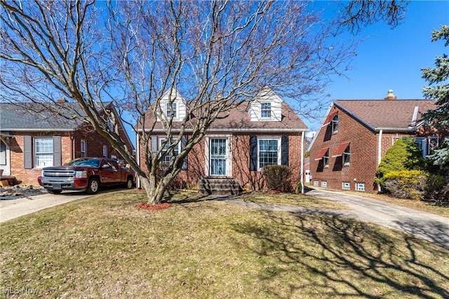 cape cod-style house with brick siding, driveway, and a front lawn