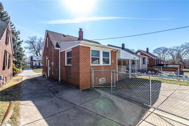 view of front of house with brick siding, a chimney, and fence