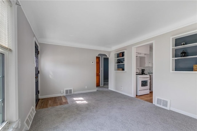 unfurnished living room featuring visible vents, arched walkways, and carpet floors