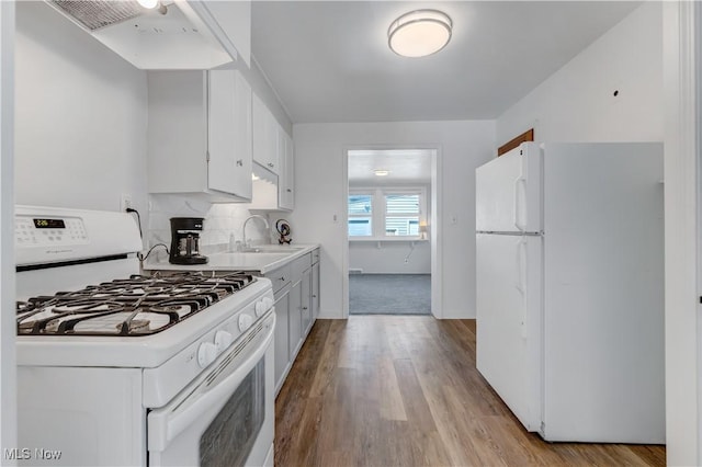 kitchen with white appliances, wood finished floors, extractor fan, and a sink