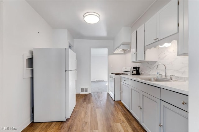 kitchen with white appliances, visible vents, a sink, light countertops, and backsplash