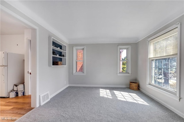 unfurnished room with visible vents, carpet, and baseboards