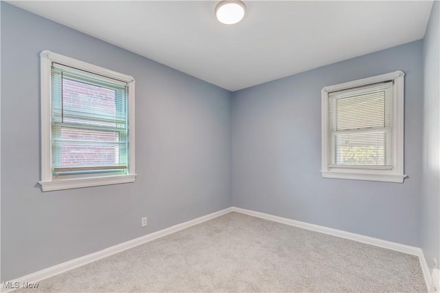 spare room with carpet flooring, baseboards, and a wealth of natural light