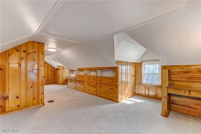 bonus room featuring vaulted ceiling, carpet, visible vents, and wood walls