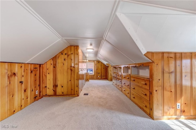 additional living space featuring visible vents, wood walls, carpet, and vaulted ceiling