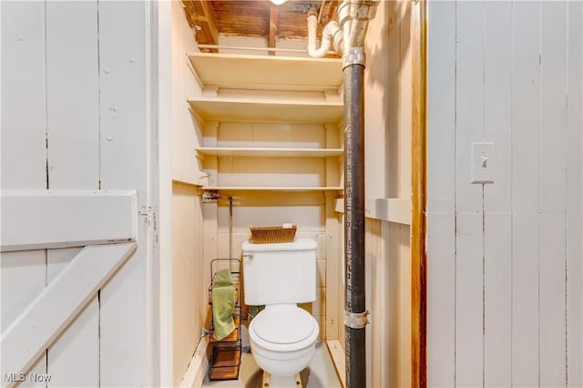 bathroom featuring wood walls and toilet