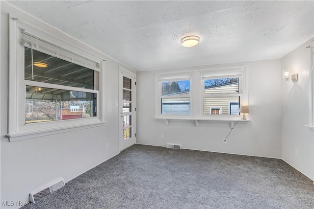 carpeted spare room featuring visible vents and a textured ceiling