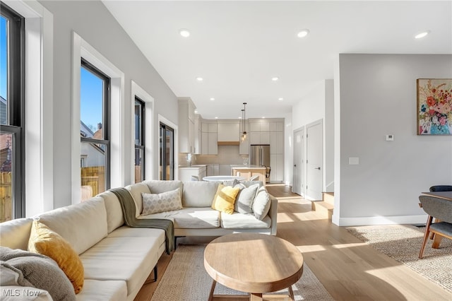 living room with recessed lighting, baseboards, and light wood-style floors