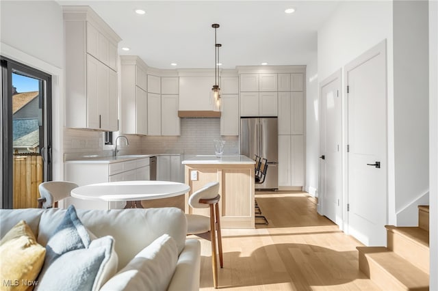 kitchen with light wood-style flooring, a center island, open floor plan, and stainless steel refrigerator