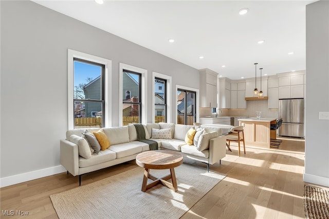 living room featuring recessed lighting, baseboards, and light wood-style floors