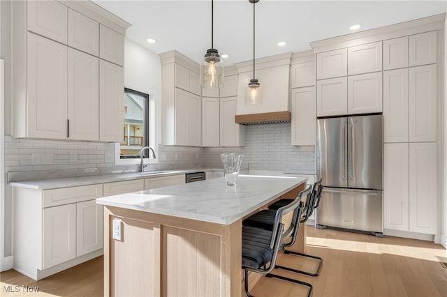 kitchen with custom exhaust hood, a sink, stainless steel appliances, light wood-type flooring, and a center island