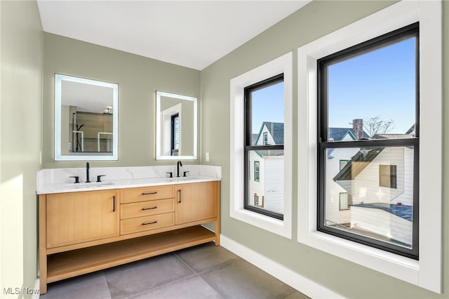 bathroom featuring double vanity, tile patterned flooring, baseboards, and a sink