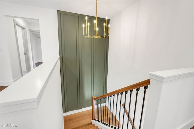 stairway with an inviting chandelier and wood finished floors