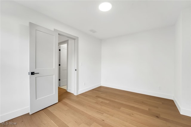 empty room featuring visible vents, light wood-style flooring, and baseboards