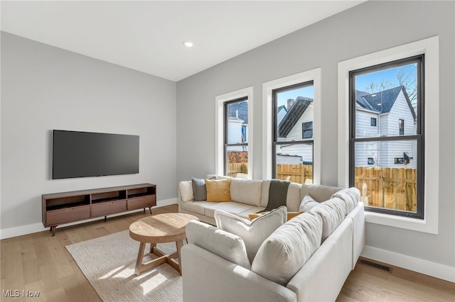 living room featuring recessed lighting, visible vents, baseboards, and light wood finished floors