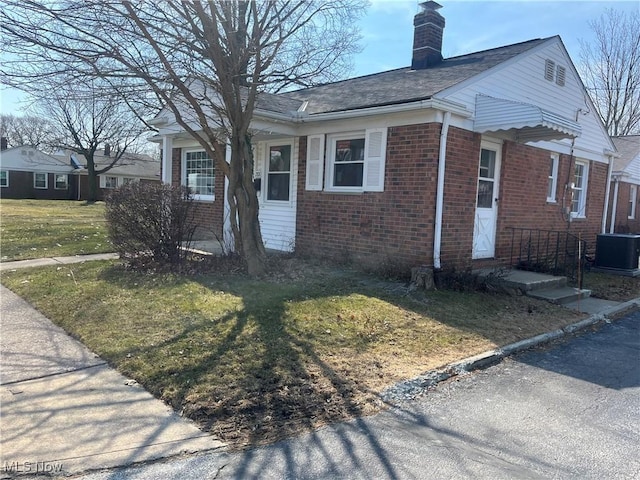 view of front of house featuring cooling unit, a front yard, brick siding, and a chimney