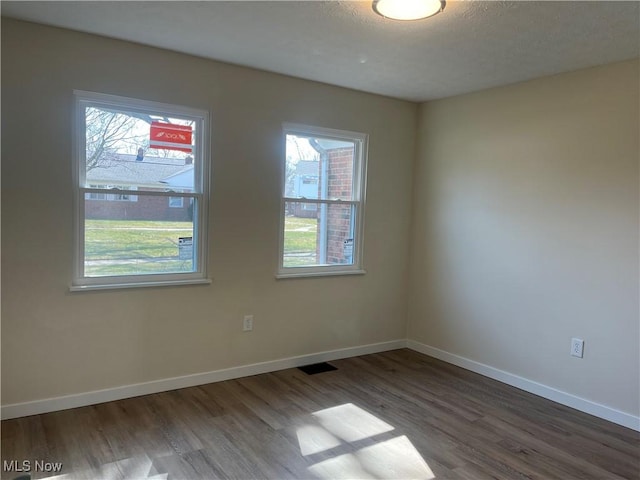 empty room with baseboards, plenty of natural light, and wood finished floors